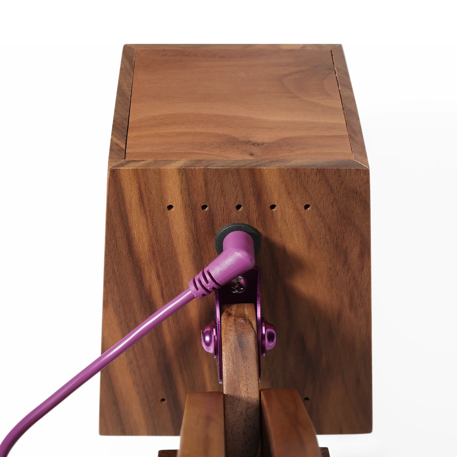 Wooden block with a purple cord plugged into it on a white background