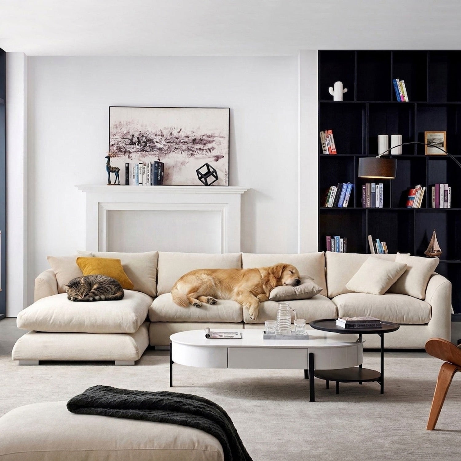 Beige sectional sofa with chaise lounge in a living room with a black bookshelf and white fireplace